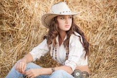 Woman over hay background. Young woman in cowboy style clothes